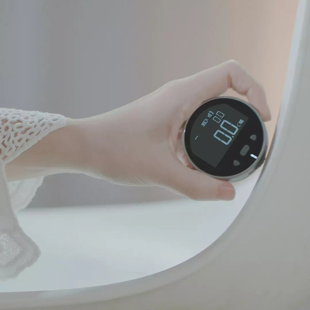 Hand holding an electronic measuring ruler with round black LCD for distance measurement