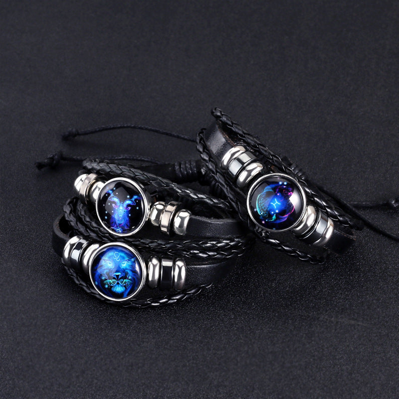 Pair of black braided bracelets with round luminous blue zodiac charms and silver accents