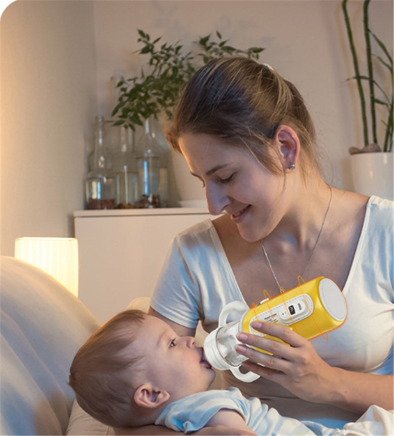 Parent holding a yellow milk bottle warmer while feeding a newborn baby