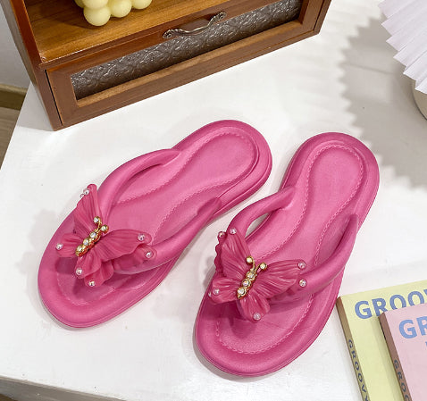 Women's pink flip-flop slippers with butterfly embellishment and rhinestone accents