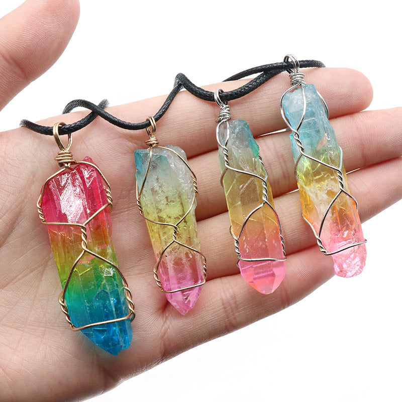 Rainbow crystal pillar pendants on black cords, shown on an open hand