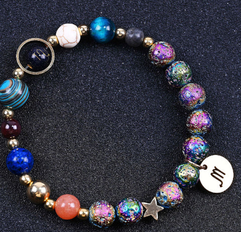 Beaded bracelet with iridescent purple/blue stones, star charm, and hand-shaped pendant