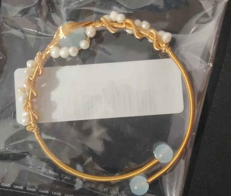 Gold pearl cuff bracelet with blue stones and white pearls in clear plastic bag
