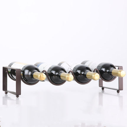 Black metal wine bottle rack with four curved slots, holding four bottles