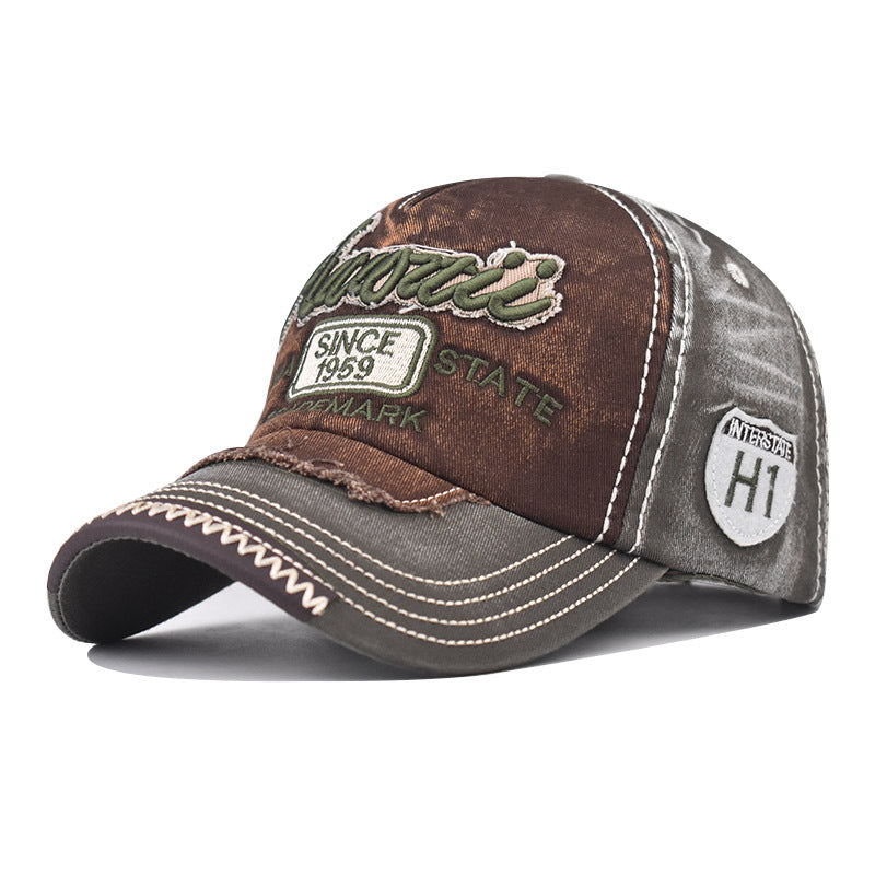Brown and dark baseball cap with green logo embroidery, curved brim, and “HI” badge