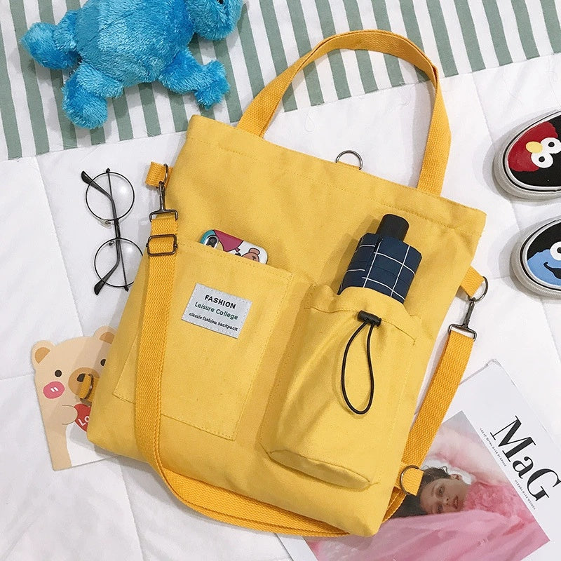 Yellow canvas tote bag with front pocket and drawstring, plaid patch detail