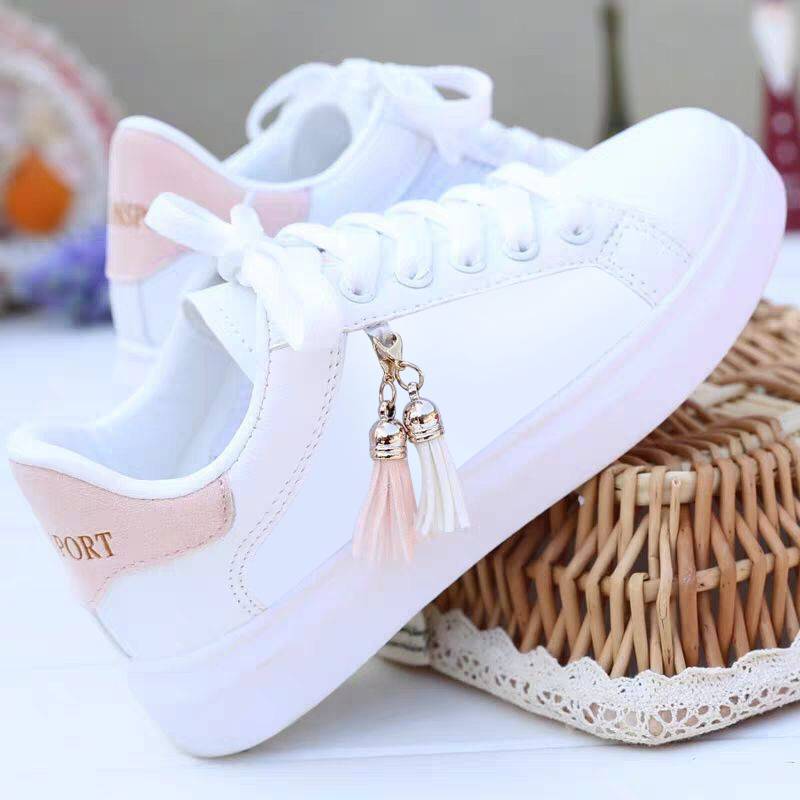 White sneakers with light pink heel accents and tassel charm, lace-up.