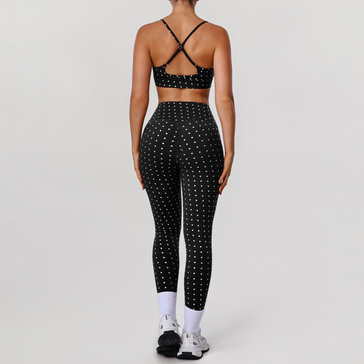 Women’s black sports bra and workout pants set with white dot print, crisscross back